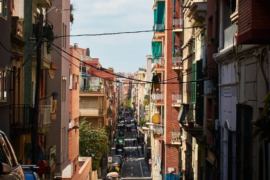Narrow street with parked cars between apartment buildings in Barcelona