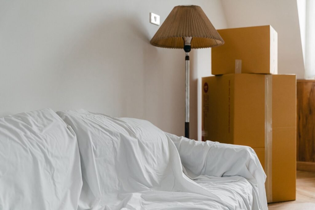 Packed moving boxes and covered furniture in a new home after relocating to the UK
